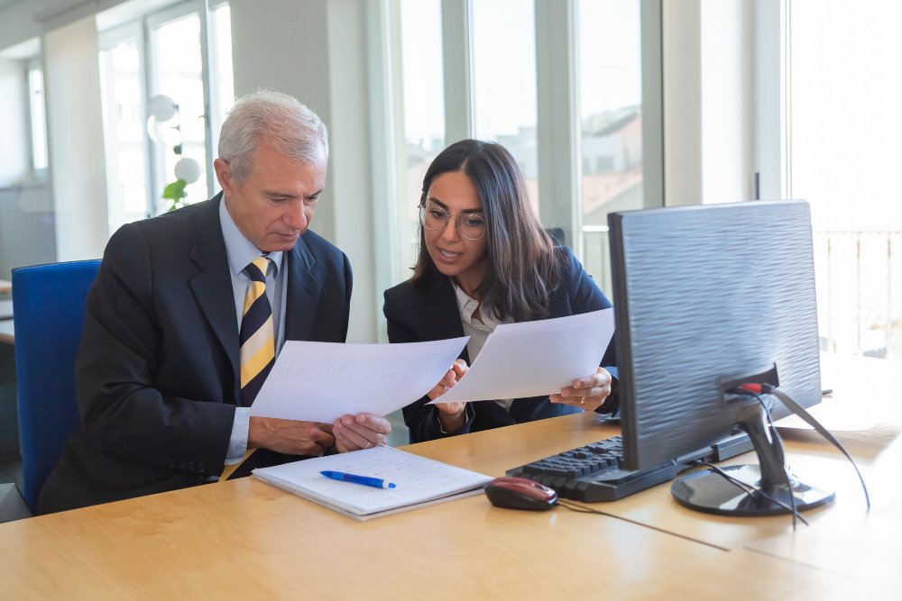 Business professionals reviewing legal documents and contracts at a desk, emphasizing collaboration in business transactions.