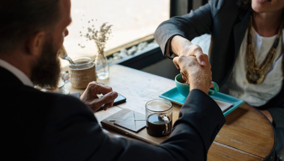 “Shareholder Agreements – Corporate Law & Business Ownership Attorney in New Jersey” Business professionals shaking hands over a table with coffee, symbolizing contract agreements and consultant discussions related to avoiding fraud and boilerplate pitfalls.
