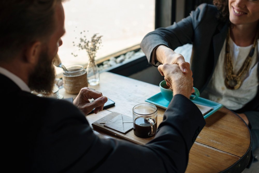 Business professionals shaking hands over a table, symbolizing partnership and collaboration in corporate agreements.