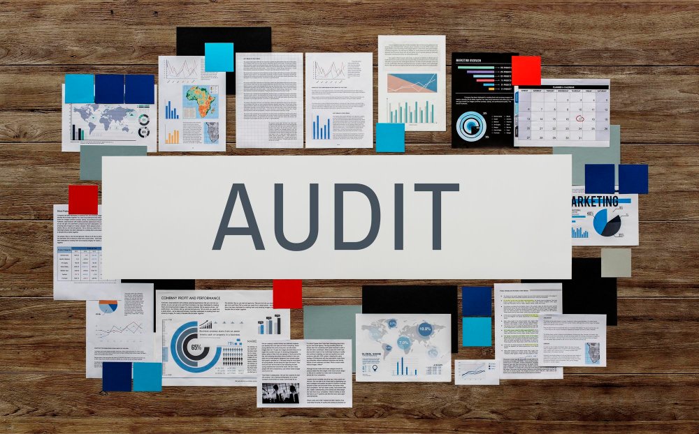 Audit documents and reports surrounding the central word "AUDIT," illustrating business compliance audits and legal precision in business operations.