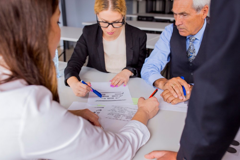 Group of professionals reviewing commercial lease documents and negotiating terms at a table, emphasizing collaboration and business strategy.
