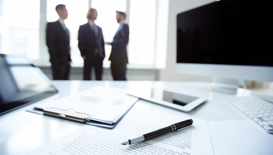 “Business attorney in New Jersey providing legal valuation guidance during corporate consultation and document review.” Business professionals discussing contract arbitration in a modern office, with a pen and documents in the foreground.