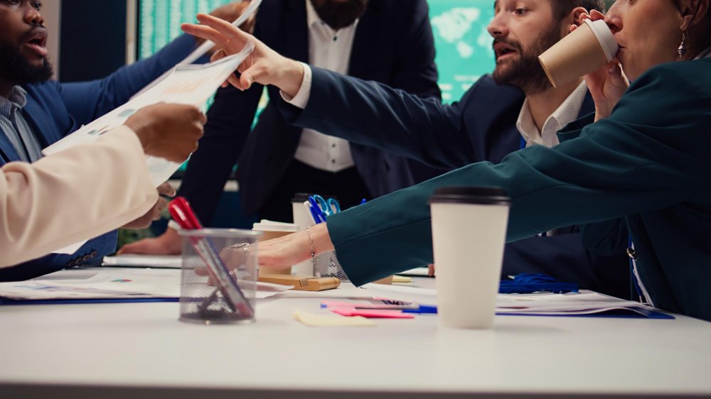 Group of business professionals engaged in a heated discussion over documents during a shareholder dispute meeting, emphasizing conflict resolution and collaboration.