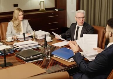 Counselors engaged in a professional discussion during a business meeting, reviewing paperwork at a conference table, with legal documents and files visible, reflecting the firm's focus on comprehensive legal guidance for businesses.