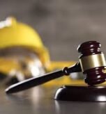 Construction Law Dispute Gavel resting on a table with a yellow hard hat in the background, symbolizing construction law and legal representation for contractors in New Jersey.