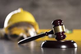 Gavel on wooden block with yellow hard hat in background, symbolizing construction law and legal compliance for businesses.