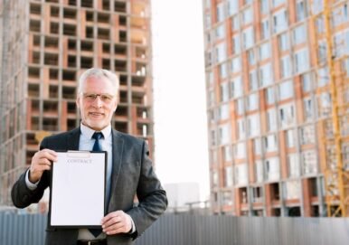 Older man in a suit holding a contract in front of a construction site, representing legal services for business contracts and negotiations.