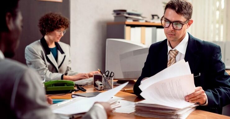 Business professionals discussing documents in an office setting, highlighting collaboration in business transactions and legal matters.