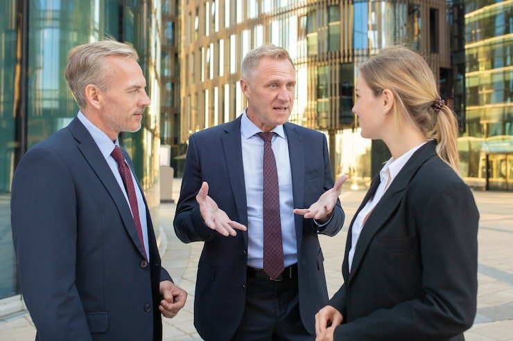 business-team-discussing-project-outdoors-men-woman-wearing-office-suits-standing-talking-outdoors-with-city-building-background-meeting-cooperation-concept_74855-6774
