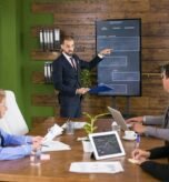 businessman-suit-pointing-charts-tv-screen-meeting-with-his-colleagues-leadership-meeting-conference-room_482257-31221